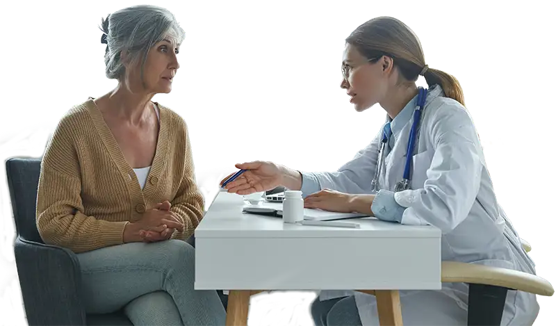 A healthcare professional reviews information with a patient at a desk.