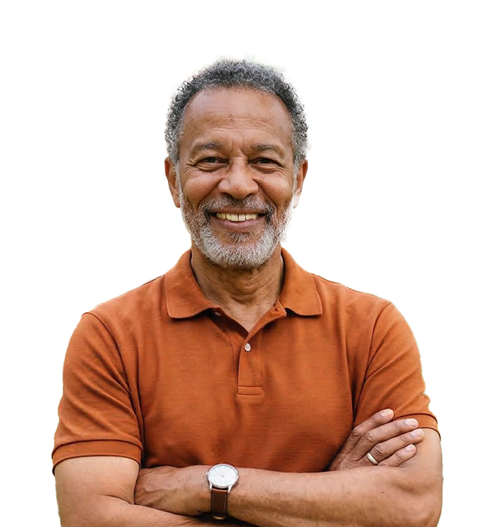 A middle-aged man with a warm smile stands with his arms crossed, wearing an orange shirt.