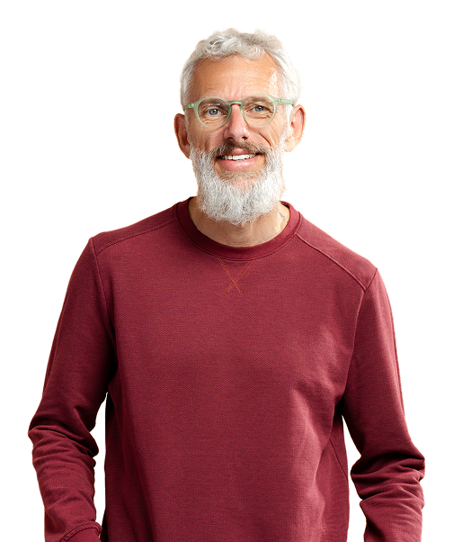 An older man with a beard smiles, wearing a burgundy sweater.